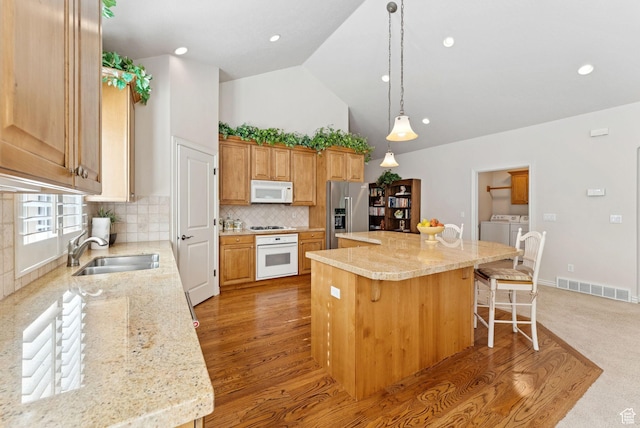 1369 E Farm Dr, Murray, UT 84117 - kitchen featuring white appliances, washing machine and clothes dryer, a kitchen island, tasteful backsplash, and a breakfast bar