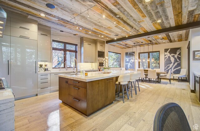 4896 Last Stand Dr, Snyderville, UT 84098 - kitchen with modern cabinets, light wood finished floors, a spacious island, light countertops, and a wood ceiling with exposed beams