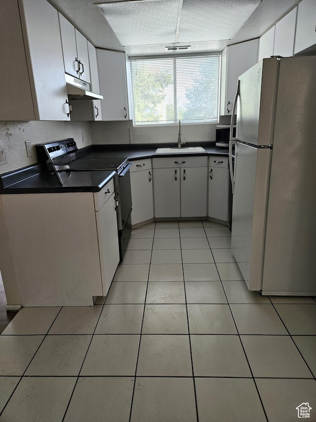 4619 S Quail Vista Ln E Unit J, Salt Lake City, UT 84117 - kitchen with freestanding refrigerator, black electric range, under cabinet range hood, dark countertops, and light tile patterned floors