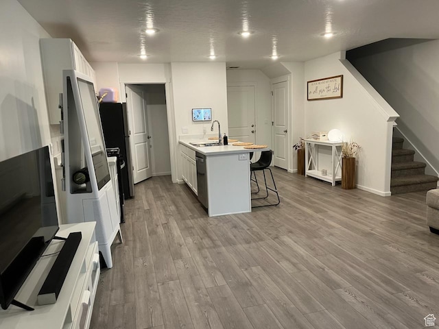 205 E Serenity Ave Unit 1213, Tooele, UT 84074 - kitchen featuring a kitchen bar, wood finished floors, light countertops, a peninsula, and dishwashing machine