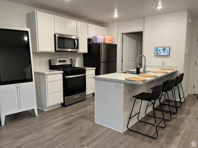 205 E Serenity Ave Unit 1213, Tooele, UT 84074 - kitchen with stainless steel appliances, wood finished floors, a breakfast bar area, white cabinetry, and recessed lighting