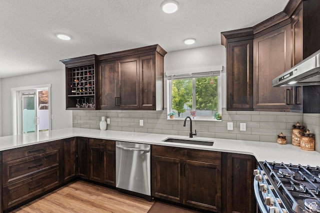 332 E 2475 N, North Logan, UT 84341 - kitchen with stainless steel dishwasher, wall chimney exhaust hood, light countertops, light wood finished floors, and dark brown cabinetry