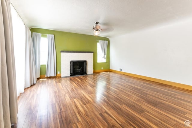 3071 Quincy Ave, Ogden, UT 84403 - unfurnished living room featuring plenty of natural light, wood finished floors, a brick fireplace, and a ceiling fan