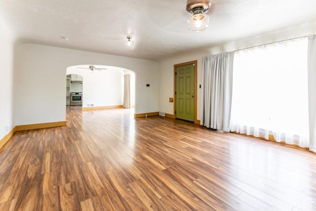 3071 Quincy Ave, Ogden, UT 84403 - unfurnished living room featuring arched walkways, wood finished floors, ceiling fan, and a textured ceiling