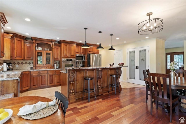 5791 S Oakwood Dr W, South Ogden, UT 84405 - kitchen featuring appliances with stainless steel finishes, brown cabinets, a kitchen island, tasteful backsplash, and light wood finished floors