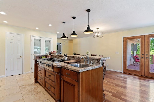 5791 S Oakwood Dr W, South Ogden, UT 84405 - kitchen with french doors, stainless steel gas stovetop, brown cabinets, ornamental molding, and decorative light fixtures