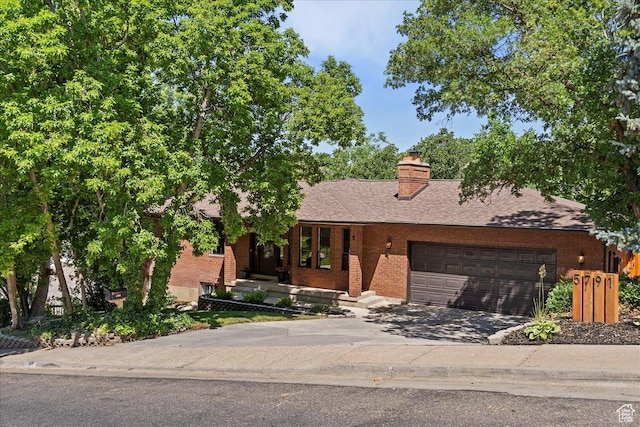 5791 S Oakwood Dr W, South Ogden, UT 84405 - view of front of house with brick siding, an attached garage, concrete driveway, and a chimney