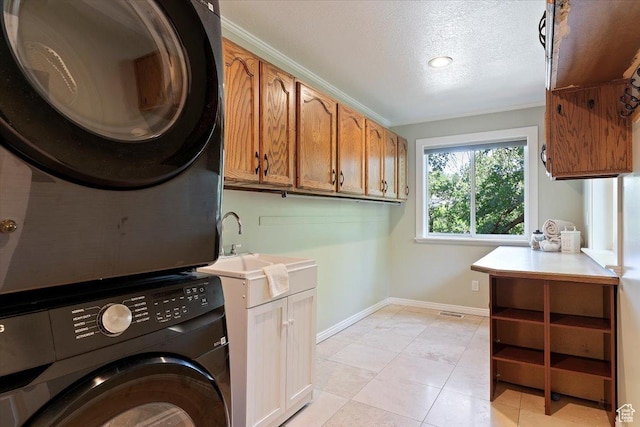 5791 S Oakwood Dr W, South Ogden, UT 84405 - laundry area with stacked washer / dryer, cabinet space, a textured ceiling, and light tile patterned floors