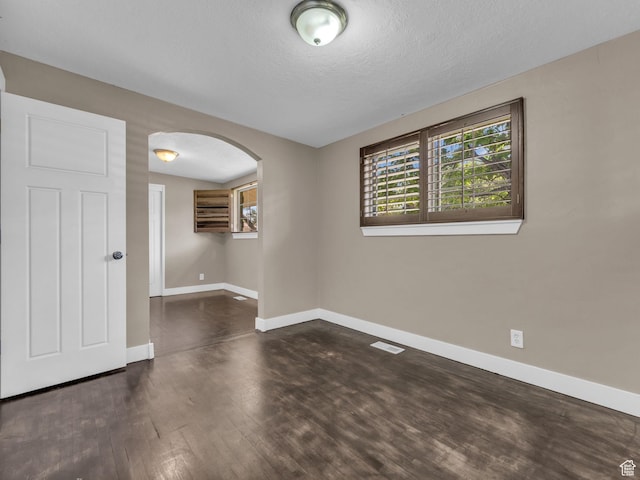 787 E Casa Blanco Cir, Midvale, UT 84047 - empty room featuring arched walkways, dark wood finished floors, and a textured ceiling