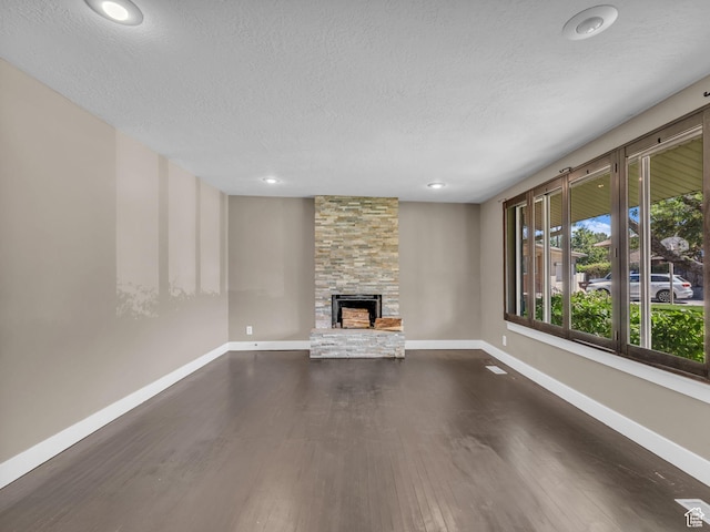 787 E Casa Blanco Cir, Midvale, UT 84047 - unfurnished living room with a stone fireplace, a textured ceiling, dark wood-style flooring, and recessed lighting