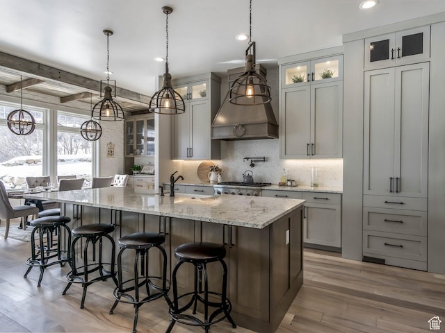 1023 W Lime Canyon Rd, Midway, UT 84049 - kitchen with an island with sink, light wood-style flooring, backsplash, custom exhaust hood, and light stone counters