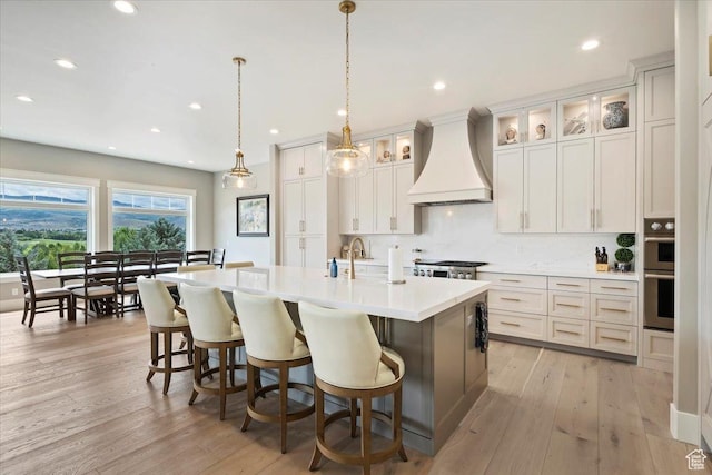 1023 W Lime Canyon Rd, Midway, UT 84049 - kitchen with custom exhaust hood, recessed lighting, an island with sink, light countertops, and a breakfast bar