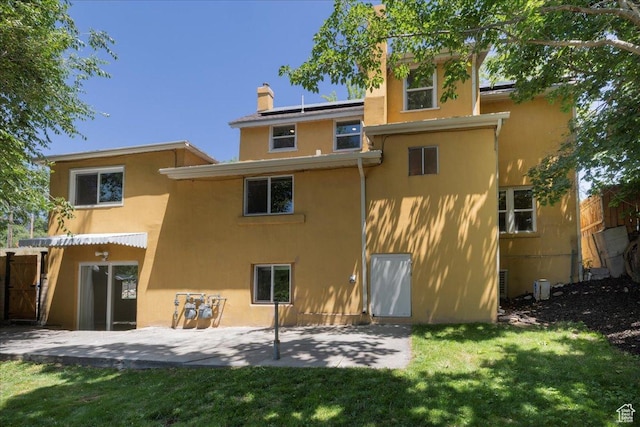 537 N Darwin St W, Salt Lake City, UT 84103 - back of property featuring stucco siding, a patio, solar panels, a yard, and a chimney