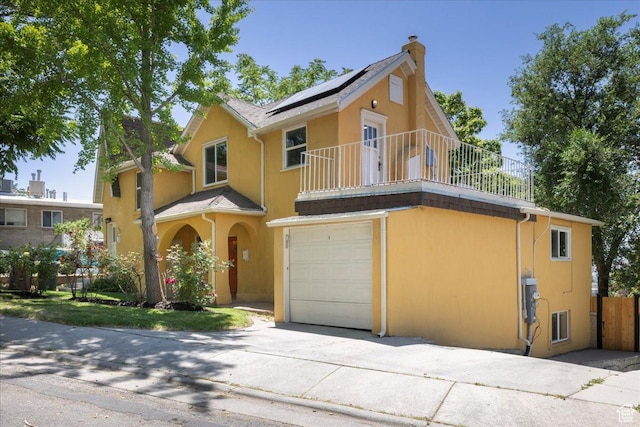 537 N Darwin St W, Salt Lake City, UT 84103 - view of front of house with a balcony, an attached garage, roof mounted solar panels, a chimney, and stucco siding