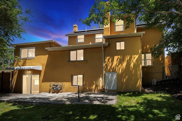 537 N Darwin St W, Salt Lake City, UT 84103 - back of property with stucco siding, a lawn, a patio area, a chimney, and roof mounted solar panels