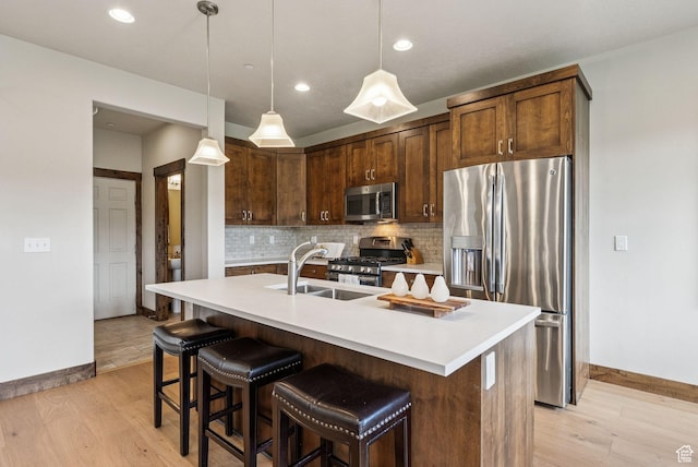 1046 W Abigail Dr, Heber City, UT 84032 - kitchen featuring stainless steel appliances, decorative backsplash, light wood finished floors, light countertops, and an island with sink