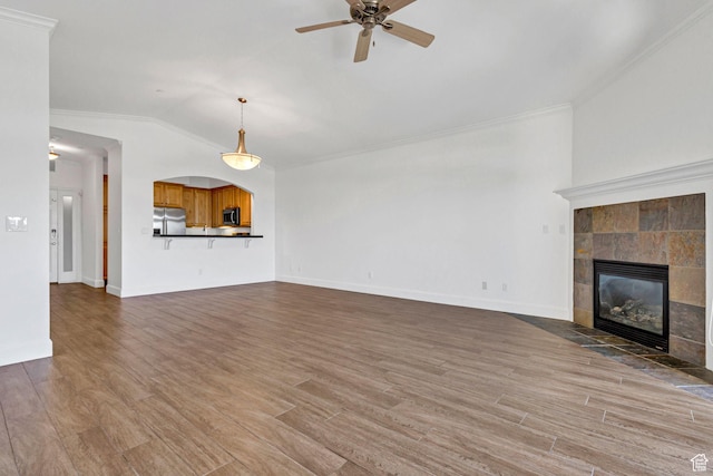 5005 N Edgewood Dr W Unit 301, Provo, UT 84604 - unfurnished living room featuring a tile fireplace, ornamental molding, lofted ceiling, a ceiling fan, and wood finished floors