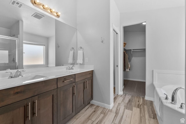 902 E 3950 S, Washington, UT 84780 - bathroom with a stall shower, double vanity, a walk in closet, a bath, and wood finished floors