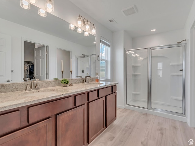 5451 N Yeager Ln, Eagle Mountain, UT 84005 - bathroom featuring a shower stall, a walk in closet, double vanity, and wood finished floors