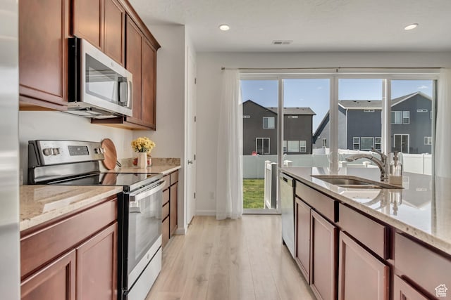 5451 N Yeager Ln, Eagle Mountain, UT 84005 - kitchen with stainless steel appliances, light wood-type flooring, light stone counters, recessed lighting, and brown cabinetry