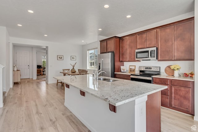 5451 N Yeager Ln, Eagle Mountain, UT 84005 - kitchen featuring stainless steel appliances, light wood-style flooring, a breakfast bar, a kitchen island with sink, and recessed lighting