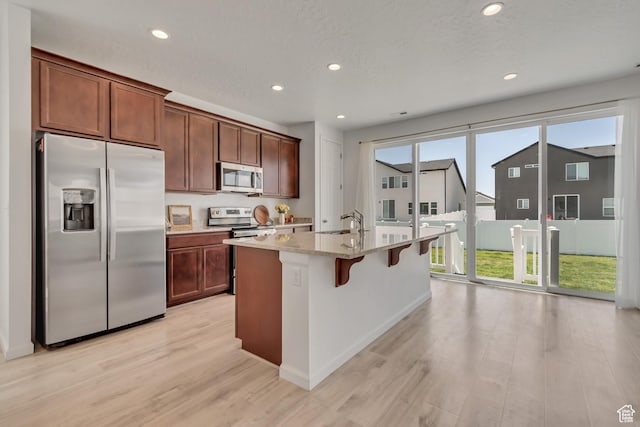 5451 N Yeager Ln, Eagle Mountain, UT 84005 - kitchen featuring stainless steel appliances, light wood finished floors, recessed lighting, a kitchen island with sink, and a breakfast bar