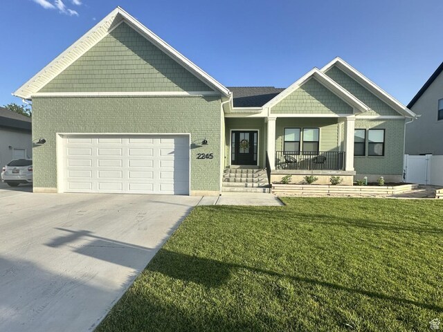 2245 W 800 S, Layton, UT 84041 - view of front of property with an attached garage, concrete driveway, covered porch, a front yard, and brick siding