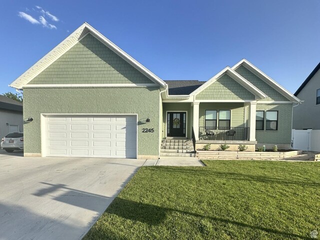 2245 W 800 S, Layton, UT 84041 - craftsman-style house featuring an attached garage, a porch, concrete driveway, a front lawn, and brick siding