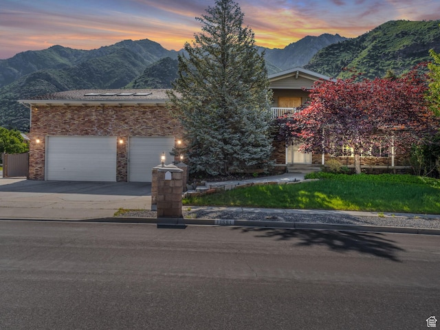 11551 S Woodhampton Dr E, Sandy, UT 84092 - view of property hidden behind natural elements featuring a mountain view, driveway, a garage, and brick siding