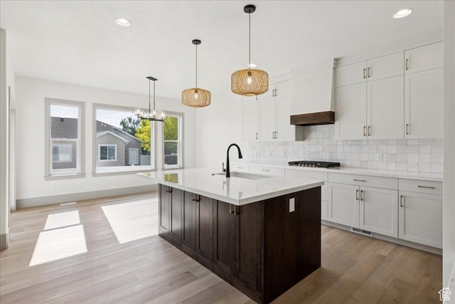 954 S Sandy Ln, Spanish Fork, UT 84660 - kitchen featuring custom range hood, stainless steel gas stovetop, light countertops, light wood-style floors, and decorative backsplash