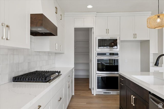 954 S Sandy Ln, Spanish Fork, UT 84660 - kitchen featuring stainless steel appliances, custom exhaust hood, white cabinets, light wood-style flooring, and light stone counters