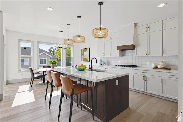954 S Sandy Ln, Spanish Fork, UT 84660 - kitchen featuring black cooktop, tasteful backsplash, light wood finished floors, light countertops, and a kitchen island with sink