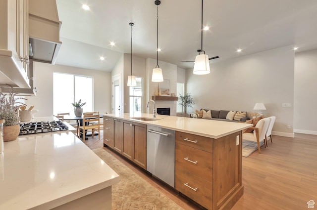 551 W Summerhill Ln, Centerville, UT 84014 - kitchen featuring appliances with stainless steel finishes, a large fireplace, open floor plan, light wood-style floors, and a kitchen island with sink