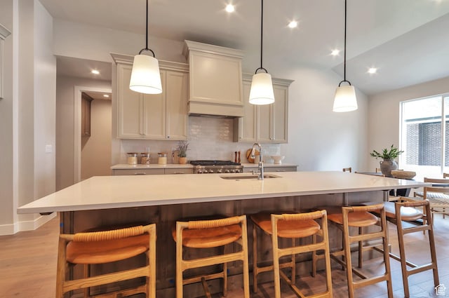 551 W Summerhill Ln, Centerville, UT 84014 - kitchen featuring backsplash, light wood-type flooring, light countertops, an island with sink, and pendant lighting