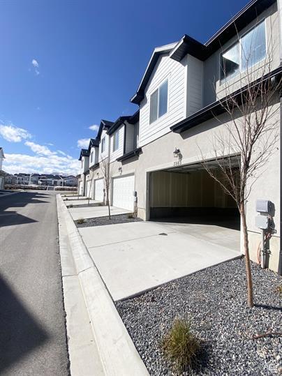 3985 W 1960 N, Lehi, UT 84043 - view of side of home featuring a garage, concrete driveway, stucco siding, and a residential view