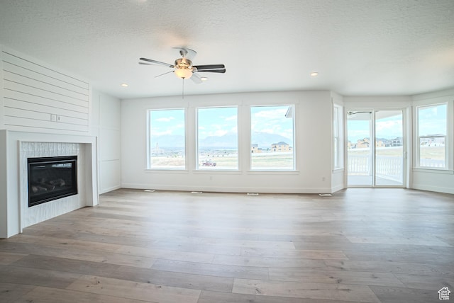 1272 S Boxelder Dr, Saratoga Springs, UT 84005 - unfurnished living room featuring a ceiling fan, wood-type flooring, a tile fireplace, a textured ceiling, and recessed lighting