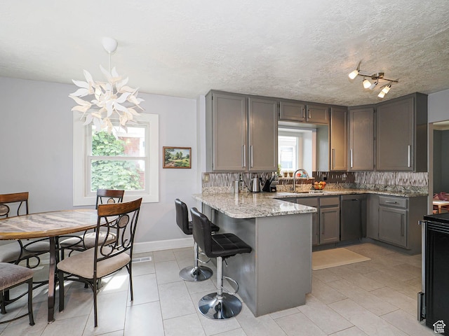 1527 E Princeton Ave S, Salt Lake City, UT 84105 - kitchen featuring stainless steel dishwasher, a peninsula, light stone counters, a chandelier, and a kitchen breakfast bar