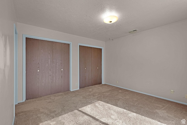 597 W Brookshire Dr, Ogden, UT 84405 - unfurnished bedroom featuring carpet, a textured ceiling, and multiple closets