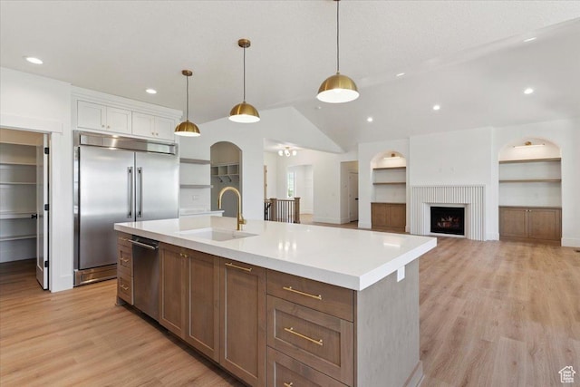 4095 N 100 E, North Ogden, UT 84414 - kitchen with stainless steel appliances, light countertops, light wood-style flooring, a kitchen island with sink, and hanging light fixtures