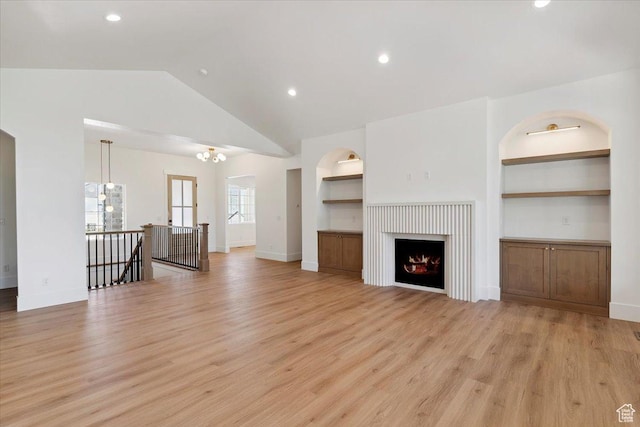 4095 N 100 E, North Ogden, UT 84414 - unfurnished living room with light wood-type flooring, built in features, vaulted ceiling, a chandelier, and recessed lighting