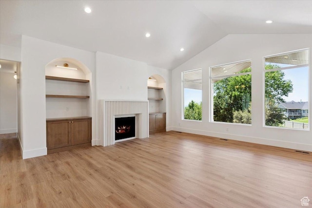 4095 N 100 E, North Ogden, UT 84414 - unfurnished living room featuring light wood-type flooring, a warm lit fireplace, built in shelves, lofted ceiling, and recessed lighting
