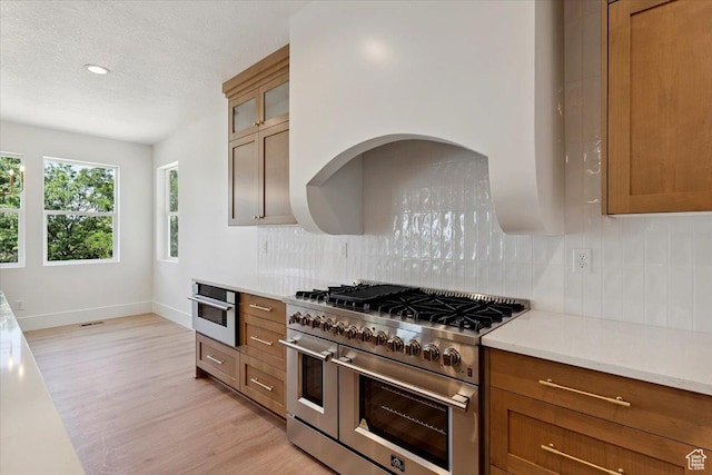 4095 N 100 E, North Ogden, UT 84414 - kitchen with appliances with stainless steel finishes, decorative backsplash, light wood finished floors, brown cabinetry, and a textured ceiling