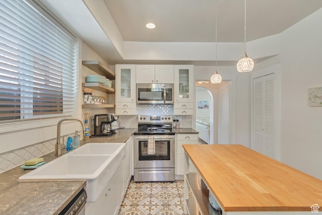 22 W 300 N, Salt Lake City, UT 84103 - kitchen featuring appliances with stainless steel finishes, butcher block countertops, white cabinets, tasteful backsplash, and glass insert cabinets