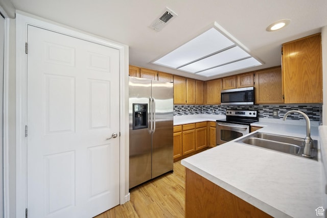 3807 S River Run Way Unit 3, Salt Lake City, UT 84119 - kitchen with appliances with stainless steel finishes, light countertops, brown cabinetry, light wood-style floors, and tasteful backsplash