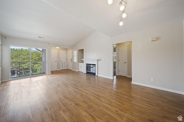 3807 S River Run Way Unit 3, Salt Lake City, UT 84119 - unfurnished living room featuring light wood-type flooring, a glass covered fireplace, and vaulted ceiling