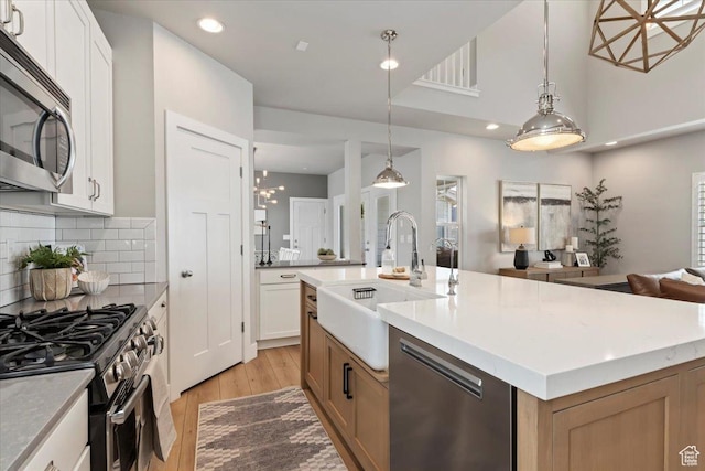 5057 W Bowstring Way S, South Jordan, UT 84009 - kitchen featuring stainless steel appliances, light wood-style floors, light countertops, recessed lighting, and a center island with sink