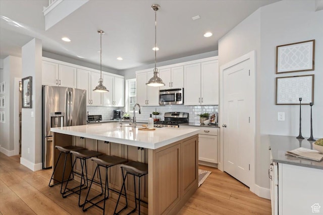 5057 W Bowstring Way S, South Jordan, UT 84009 - kitchen featuring appliances with stainless steel finishes, light wood finished floors, tasteful backsplash, a breakfast bar, and recessed lighting