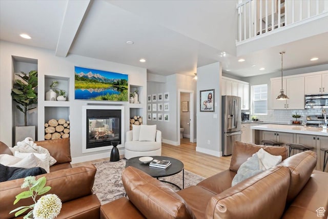 5057 W Bowstring Way S, South Jordan, UT 84009 - living room with light wood-type flooring, a glass covered fireplace, recessed lighting, and built in shelves
