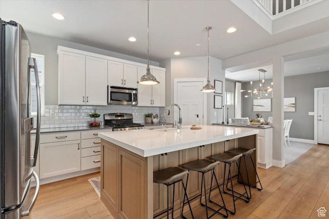 5057 W Bowstring Way S, South Jordan, UT 84009 - kitchen featuring appliances with stainless steel finishes, a kitchen bar, backsplash, light wood finished floors, and a center island with sink