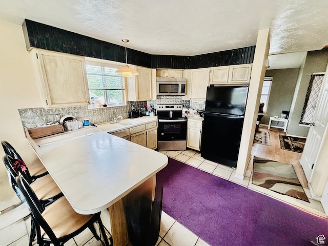 4946 W Pawnee Dr, West Jordan, UT 84081 - kitchen featuring stainless steel appliances, a peninsula, tasteful backsplash, light countertops, and light tile patterned floors
